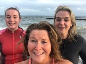 Three women smiling and posing for a selfie in front of the sea, for Galway Simons Dip a Day in May